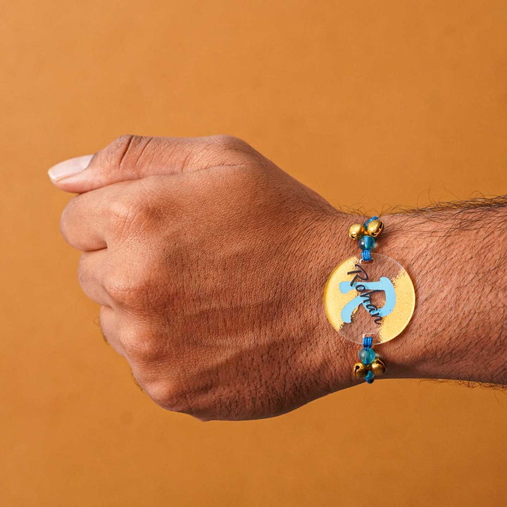 Personalized Handmade Alphabet Golden Acrylic Rakhi With Roli Chawal - Wrist Wearing Rakhi Straight Angle