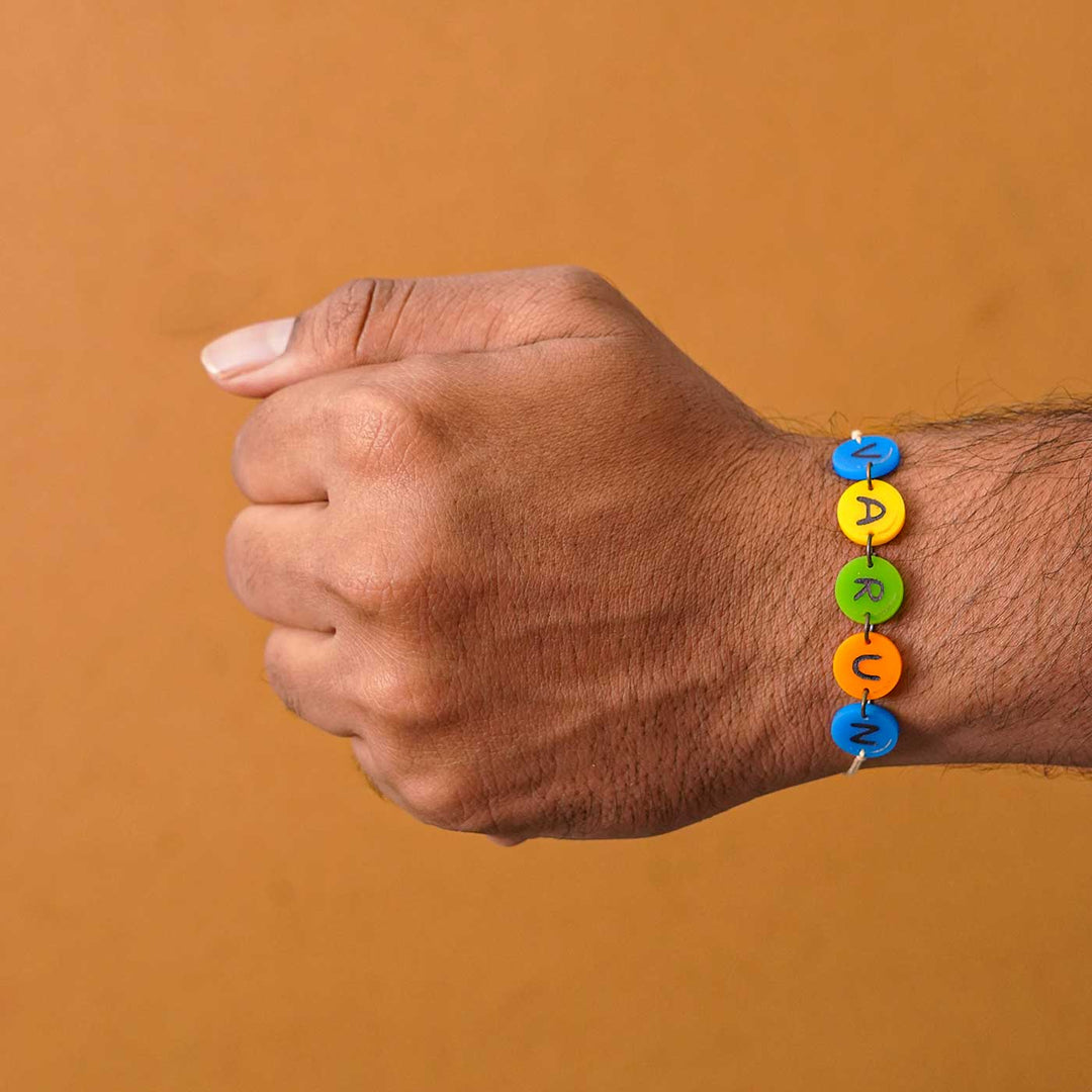 Personalized Handmade Gems Acrylic Rakhi With Roli Chawal - Worn on wrist showing name beads