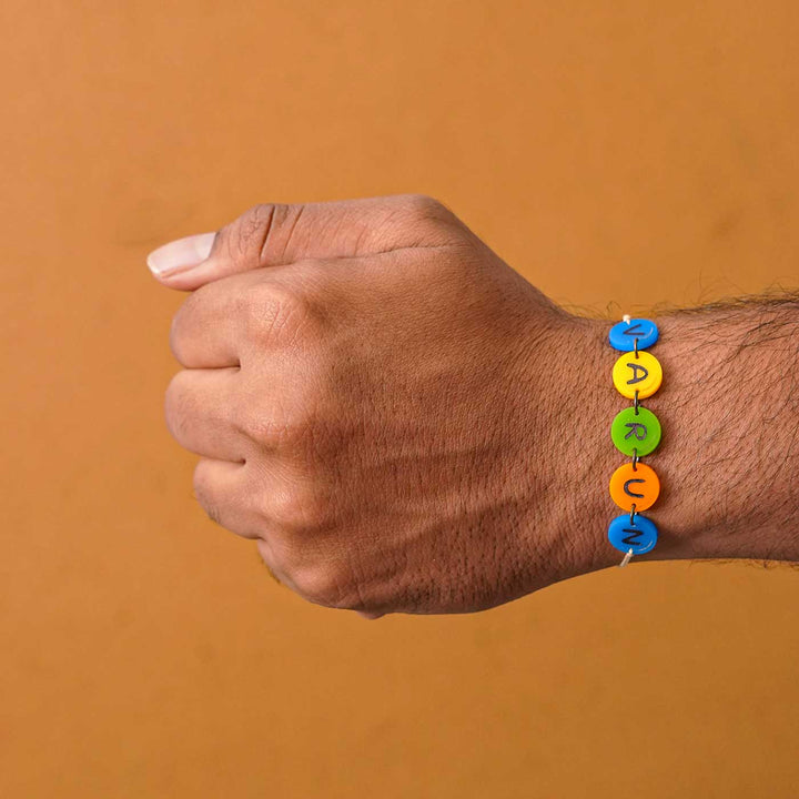 Personalized Handmade Gems Acrylic Rakhi With Roli Chawal - Worn on wrist showing name beads