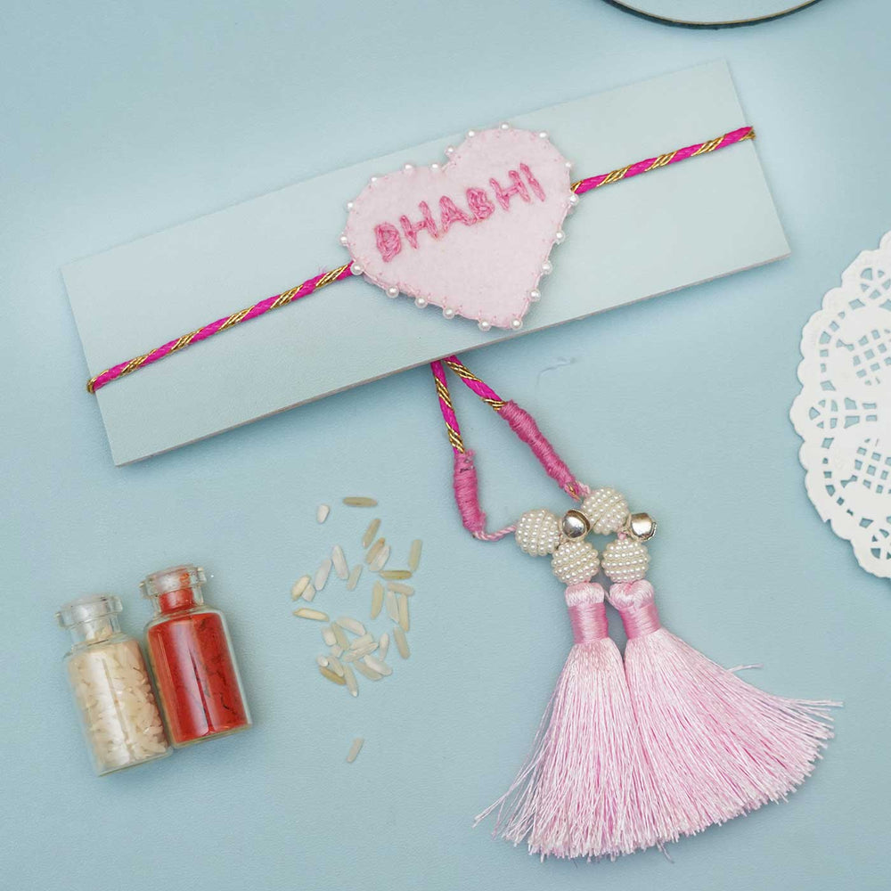 Handmade Pink Heart Felt Rakhi With Roli Chawal For Bhabhi - Flat Lay with Tassels and Spices