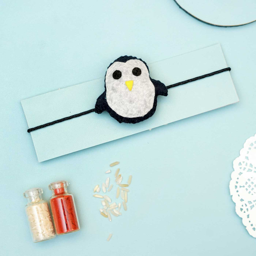Handmade Penguin Felt Rakhi With Roli Chawal - Front view of penguin bracelet display