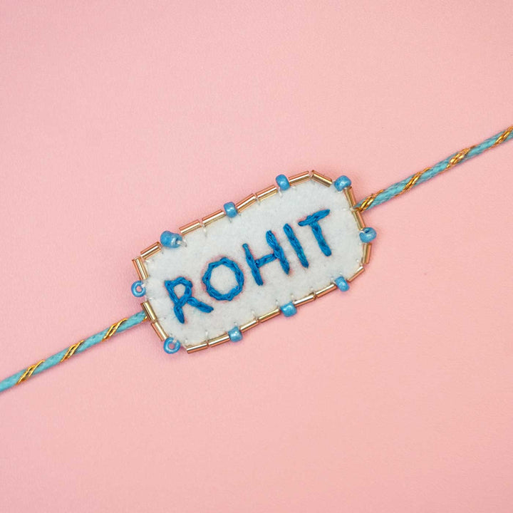 Personalized Handmade Blue Rectangle Felt Rakhi With Roli Chawal - Close-up of Name Embroidery