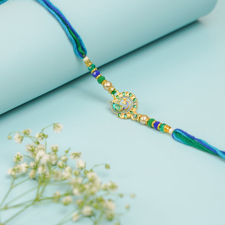 Handmade Blue And Green Peacock Jadtar Rakhi With Roli Chawal - Front View with Floral Accent