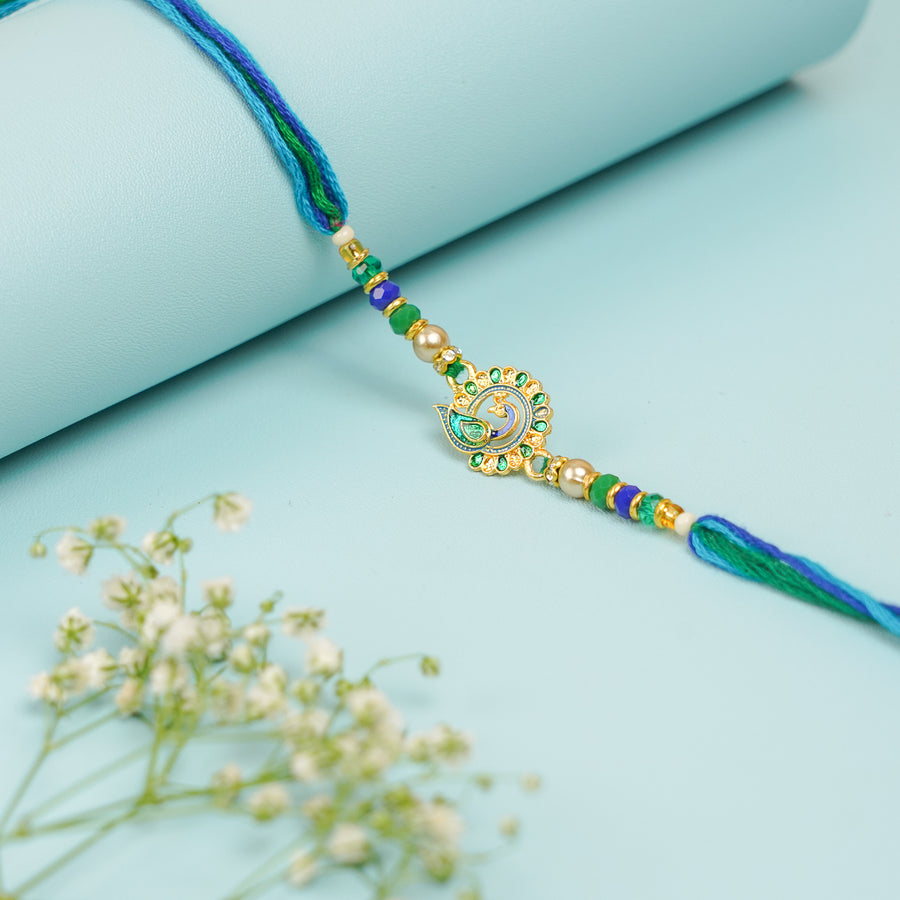 Handmade Blue And Green Peacock Jadtar Rakhi With Roli Chawal - Front View with Floral Accent