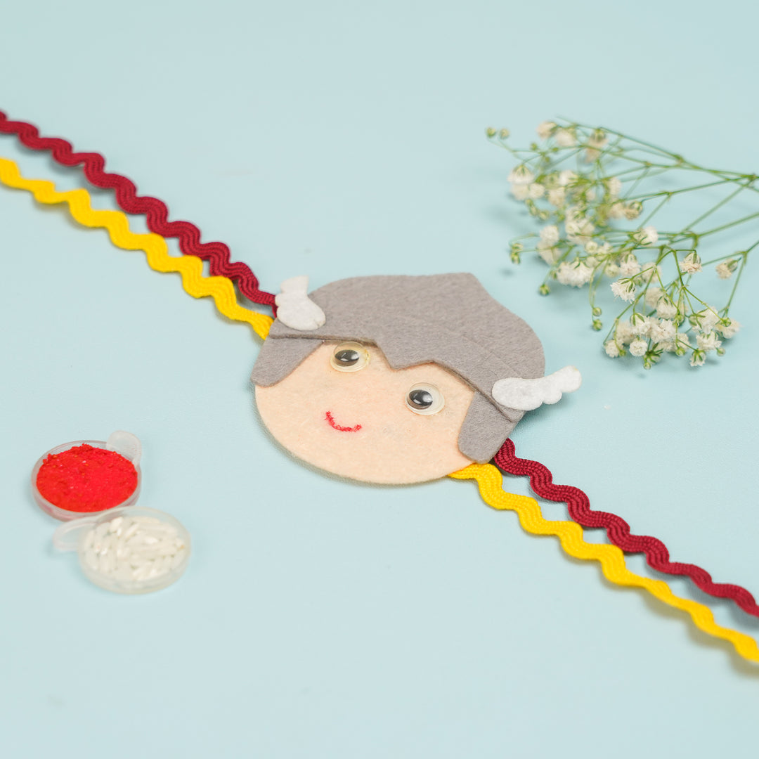 Handmade Thor Theme Felt Kids Rakhi With Roli Chawal - Flat Lay with Accessories and Flowers