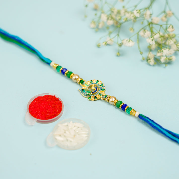 Handmade Blue And Green Peacock Jadtar Rakhi With Roli Chawal - Front View with Accessories Showcase