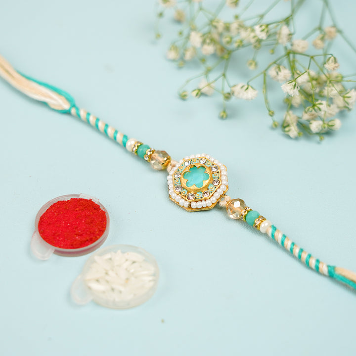 Handmade Sea Green Judtar Rakhi With Roli Chawal - Flat Lay with Accessories and Flowers