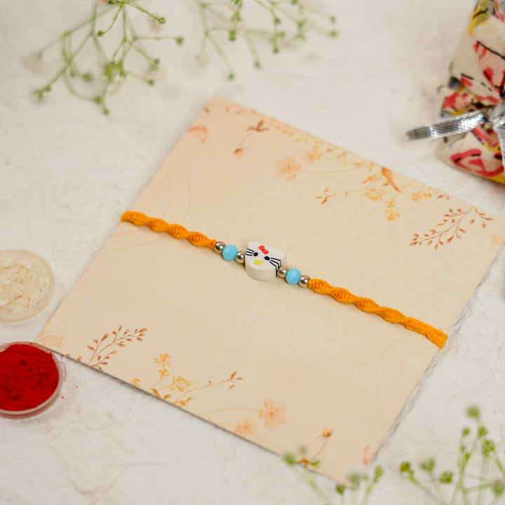 Handmade Hello Kitty Kids Rakhi With Roli Chawal - Angled Packaging and Accessory Arrangement