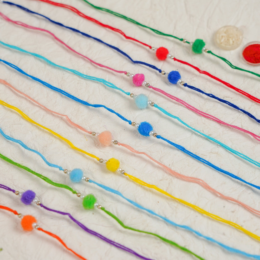 Handmade Small Pompom Rakhi With Roli Chawal Set Of 12 - Flat Lay Showing Bracelet Colors