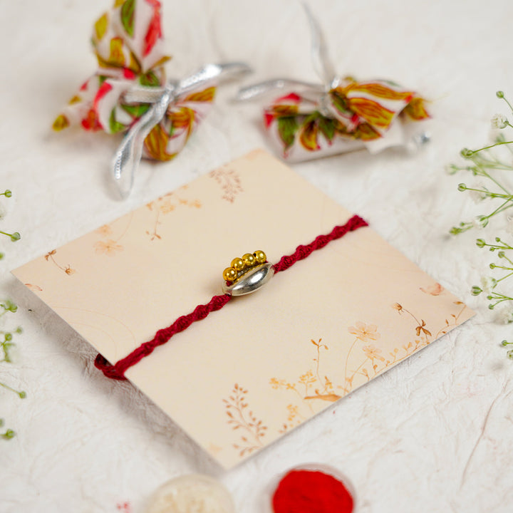 Handmade Beaded Shell Rakhi With Roli Chawal - Angled View with Accessories