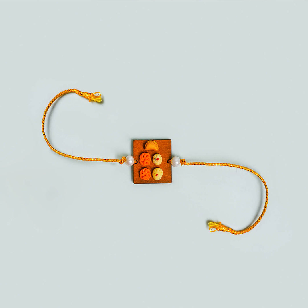 Handmade Food Themed Clay Rakhi 2 - Flat lay on plain background