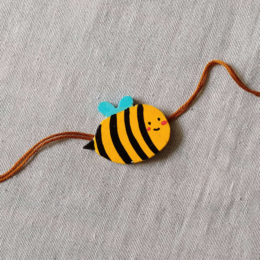 Handpainted Quirky Wooden Rakhi With Roli Chawal 6 - Close-up of Bee Charm Bracelet