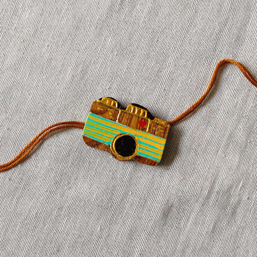 Handpainted Quirky Wooden Rakhi With Roli Chawal 7 - Close-up of Camera Rakhi