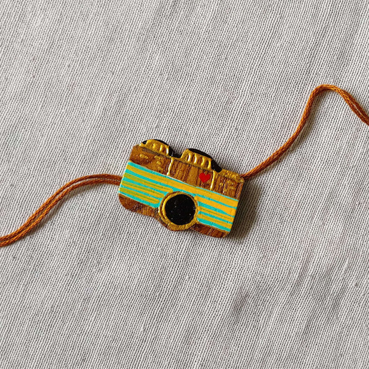 Handpainted Quirky Wooden Rakhi With Roli Chawal 7 - Close-up of Camera Rakhi