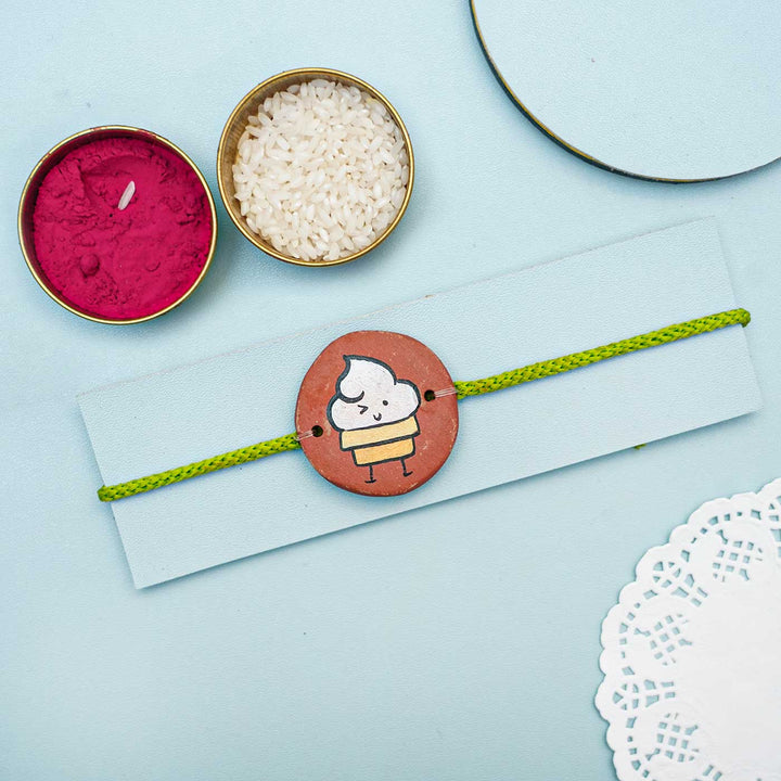 Hand Painted Ice Cream Theme Terracotta Rakhi With Roli Chawal - Styled Product Display with Traditional Items