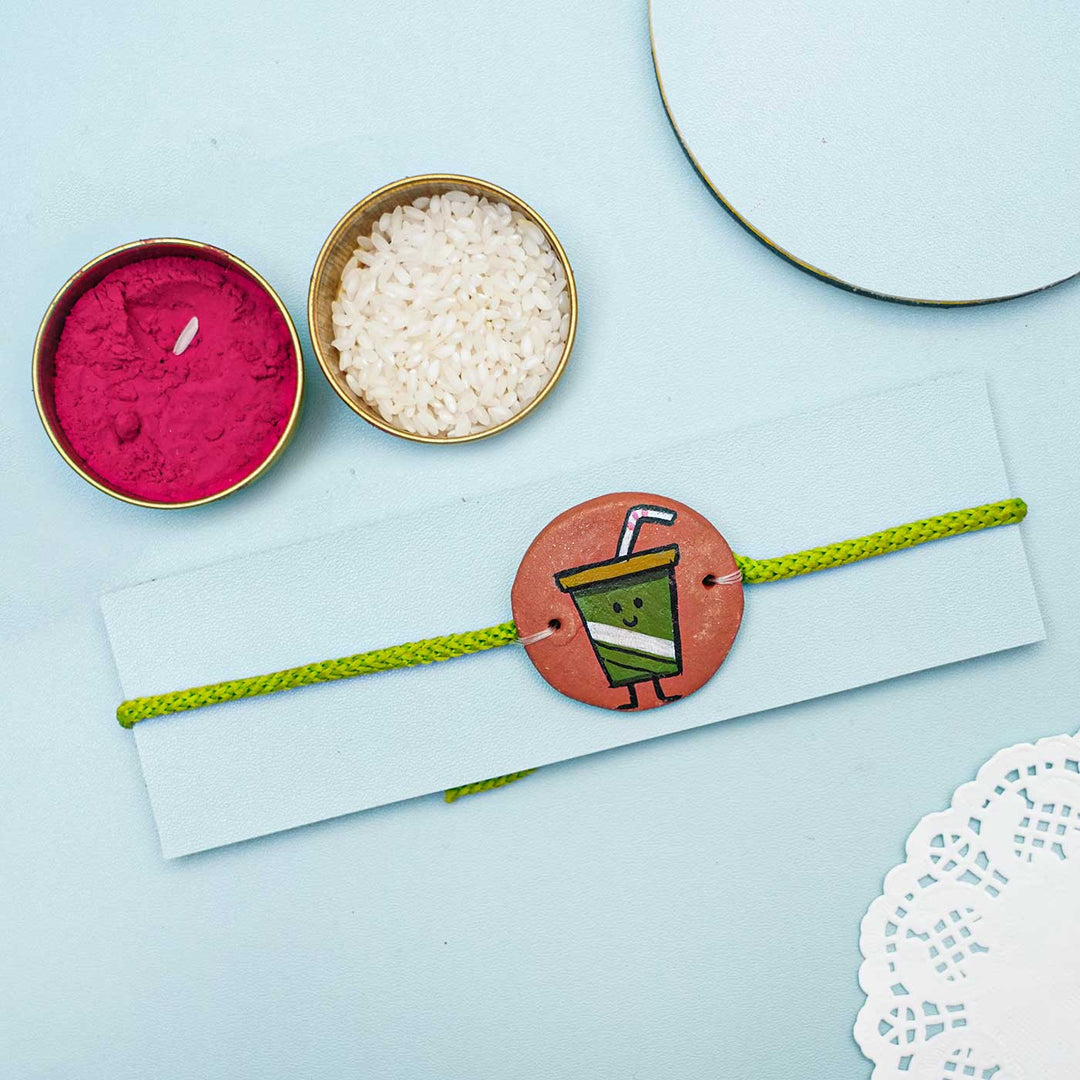 Hand Painted Pizza Terracotta Rakhi With Roli Chawal - Styled Flat Lay with Accessories