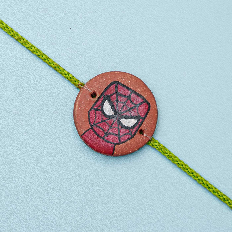 Hand Painted Spiderman Terracotta Rakhi With Roli Chawal For Kids - Close-up of decorative bracelet centerpiece