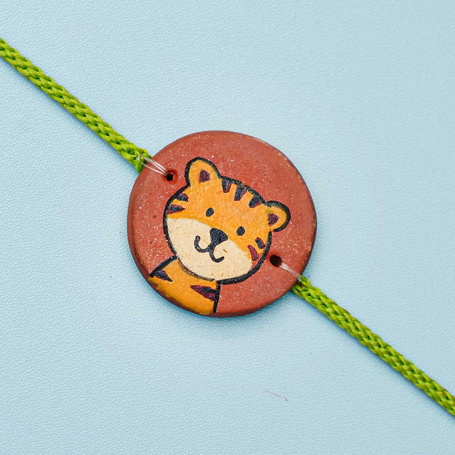 Hand Painted Tiger Terracotta Rakhi With Roli Chawal For Kids - Close-up of Charm Detail
