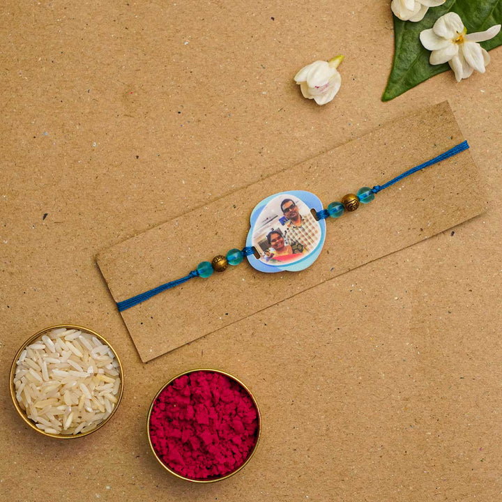 Photo Personalized Handmade Photo Acrylic Rakhi With Roli Chawal - Blue rakhi displayed with traditional items