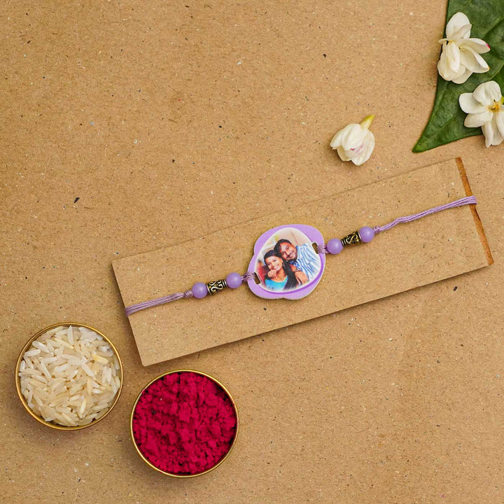 Photo Personalized Handmade Photo Acrylic Rakhi With Roli Chawal - Purple rakhi displayed with traditional items