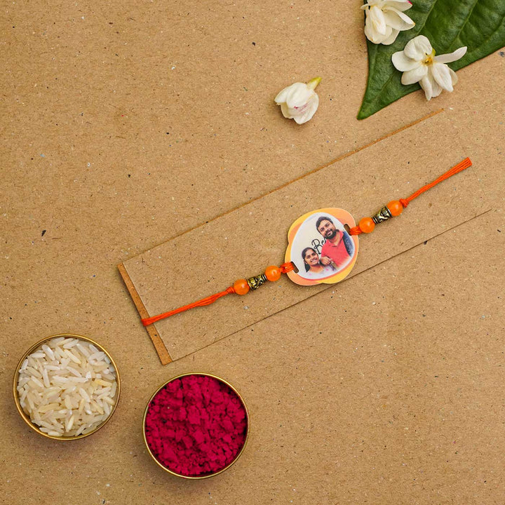 Photo Personalized Handmade Photo Acrylic Rakhi With Roli Chawal - Rakhi displayed with traditional items