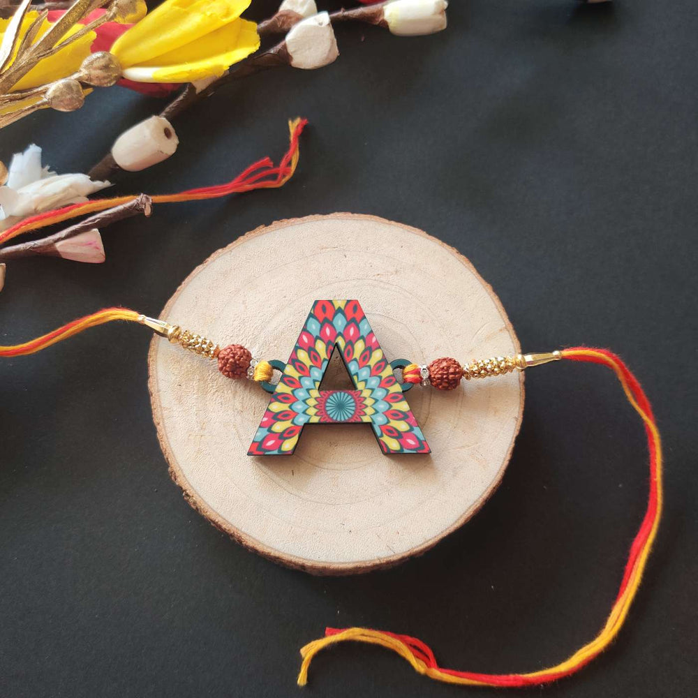 Personalized Handmade Printed Alphabet Wooden Rudraksha Rakhi With Roli Chawal - Flat Lay on Wood Slice