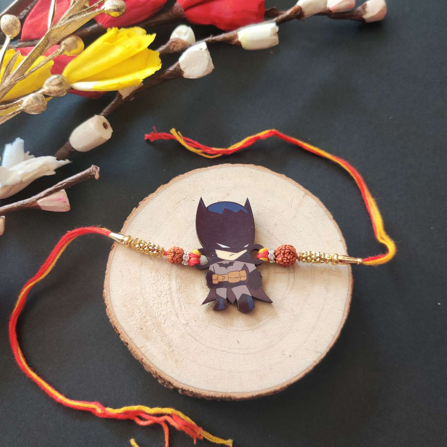 Handmade Printed Batman Wooden Rudraksha Rakhi With Roli Chawal - Flat Lay with Decorative Flowers