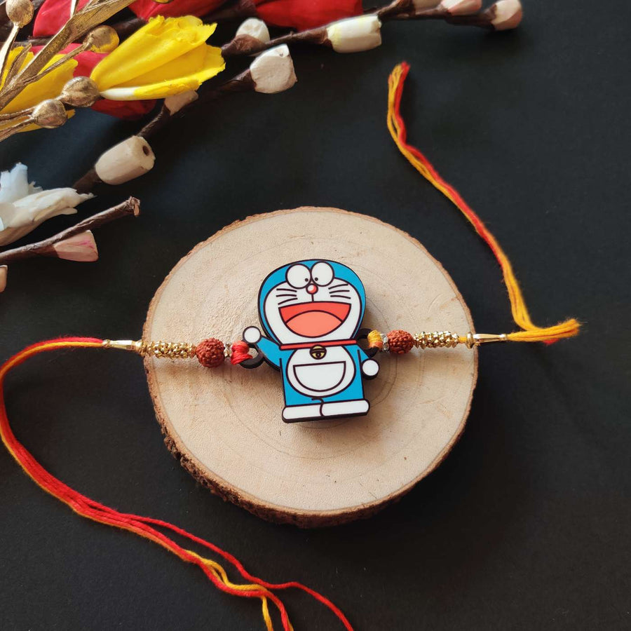 Handmade Printed Doraemon Wooden Rudraksha Rakhi With Roli Chawal - Front View on Wooden Base