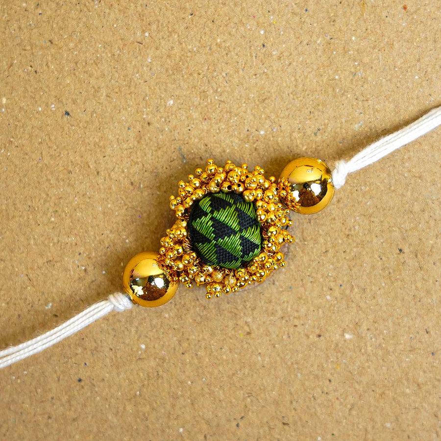 Handmade Green And Gold Fabric Rakhi With Roli Chawal - Close-up of Rakhi design