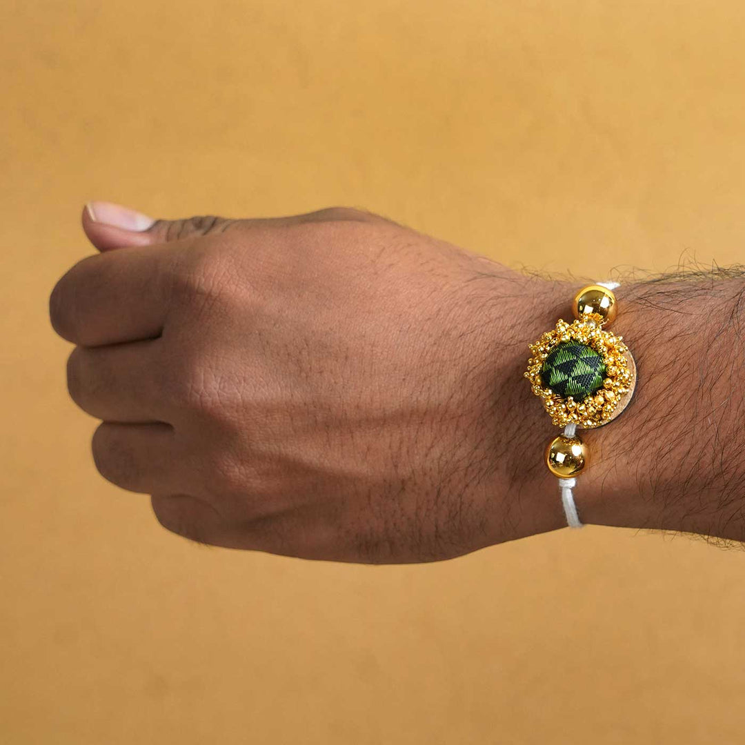 Handmade Green And Gold Fabric Rakhi With Roli Chawal - Worn on wrist display