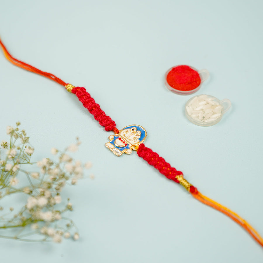 Handmade Macrame Doremon Theme Metal Rakhi With Roli Chawal - Front View with Decorative Items