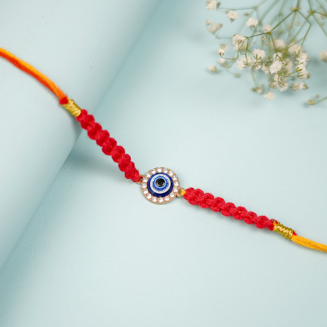 Handmade Macrame Circle Evil Eye Metal Rakhi With Roli Chawal - Close-up Laid on Curved Surface