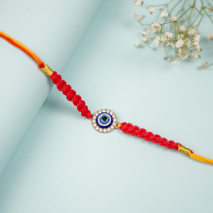 Handmade Macrame Circle Evil Eye Metal Rakhi With Roli Chawal - Close-up Laid on Curved Surface