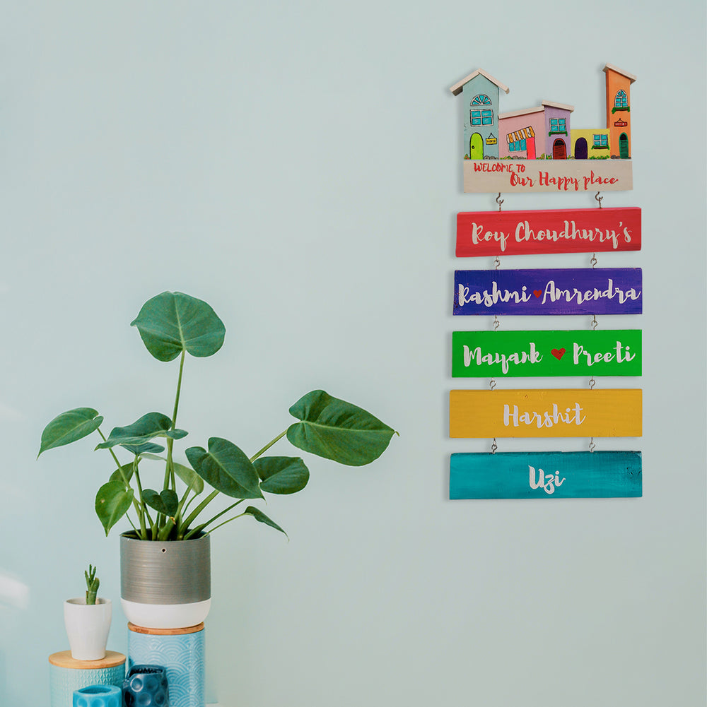 Handpainted Wooden Hanging House Name Plate - Mounted on Wall with Plant Nearby