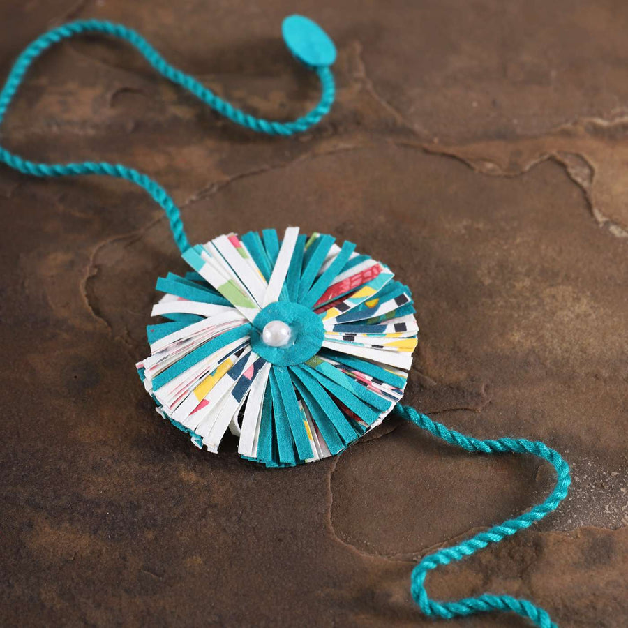 Handmade Ecofriendly Blue Recycled Paper Rakhi With Roli Chawal - Close-up on Surface
