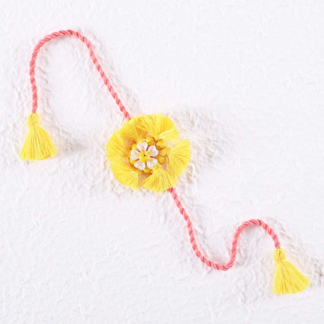 Handmade Beaded Tassel Flower Cotton Rakhi With Roli Chawal - Flat Lay on White Surface