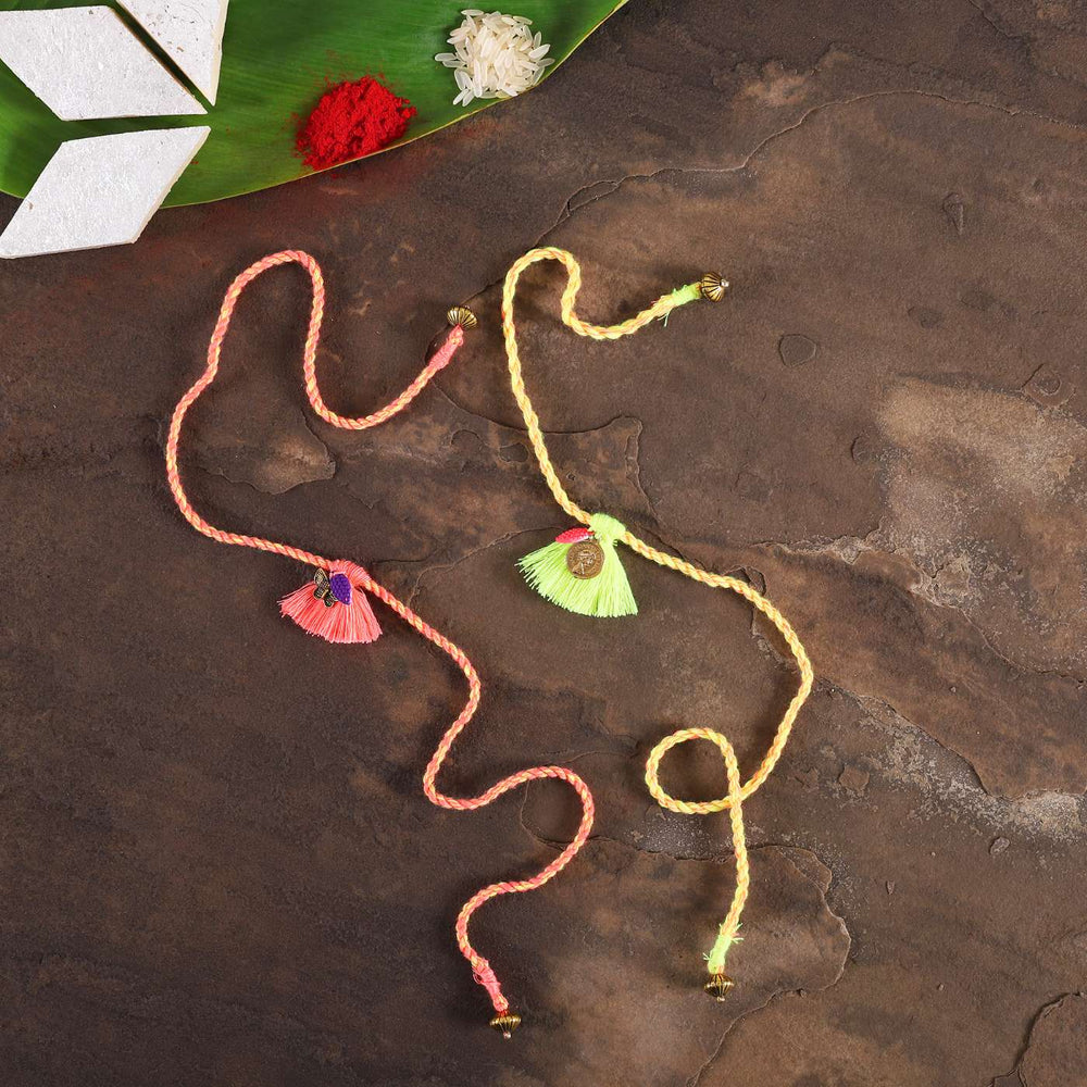Handmade Coral And Green Tassel Rakhi With Roli Chawal Set Of 2 - Flat lay with decorative items
