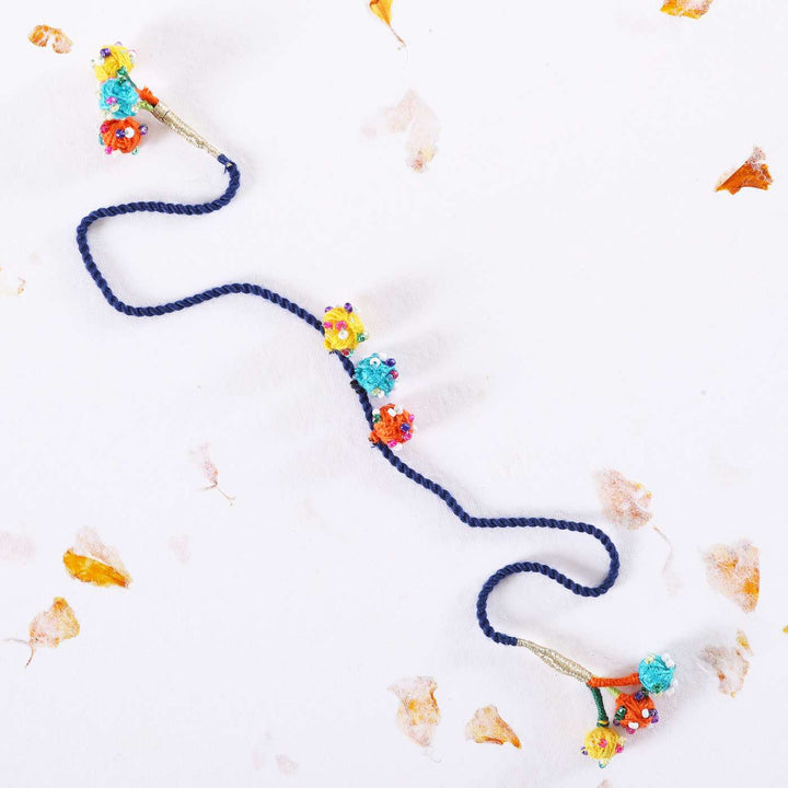 Handmade Beaded Dark Blue Dori Rakhi With Roli Chawal - Flat lay with decorative petals