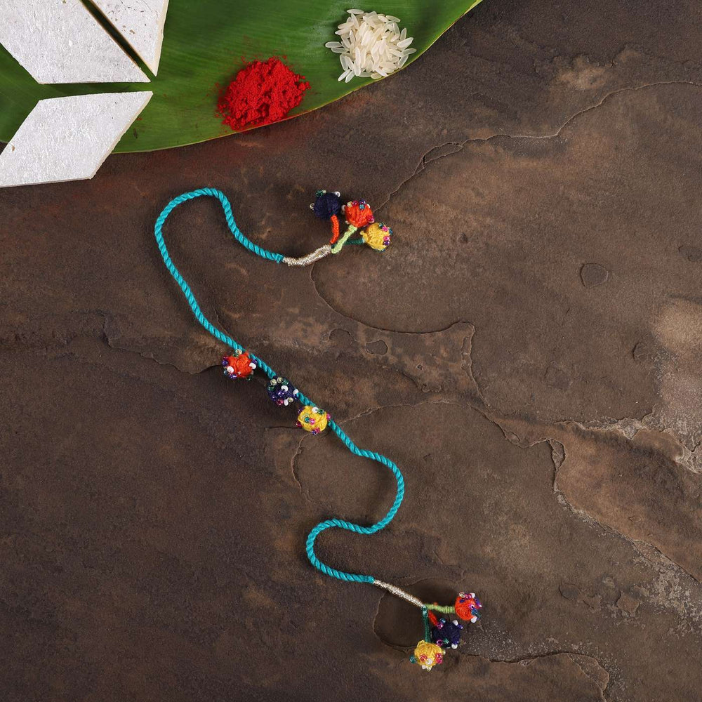 Handmade Beaded Light Blue Dori Rakhi With Roli Chawal - Flat Lay with Traditional Items