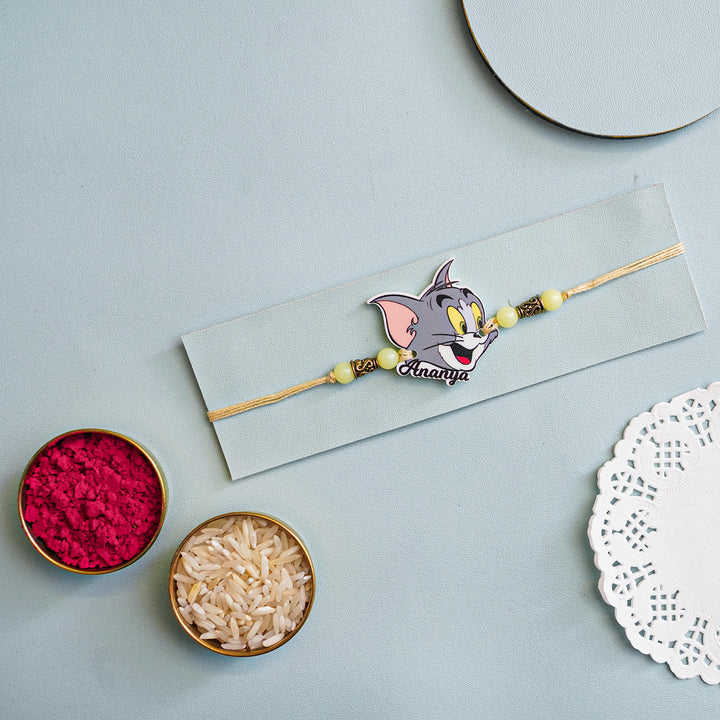 Personalized Handmade Tom And Jerry Acrylic Kids Rakhi With Roli Chawal - Flat Lay with Rakhi and Puja Items