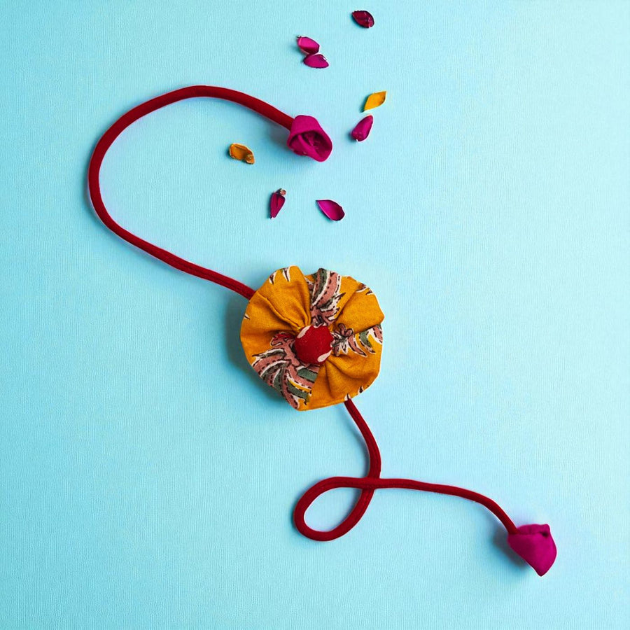 Handmade Yellow Flower Pom Pom Design Upcycled Fabric Rakhi With Roli Chawal For Brother - Full View with Decorative Petals