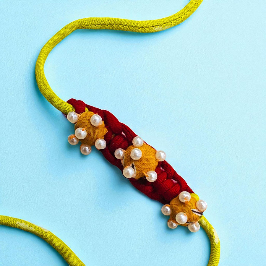 Handmade Golden Coiled Pearl Upcycled Fabric Rakhi With Roli Chawal For Brother - Close-up of Decorative Section