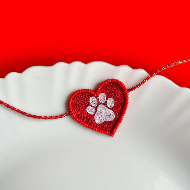Handmade Beaded Paw Heart Rakhi With Roli Chawal - Displayed on a white decorative plate