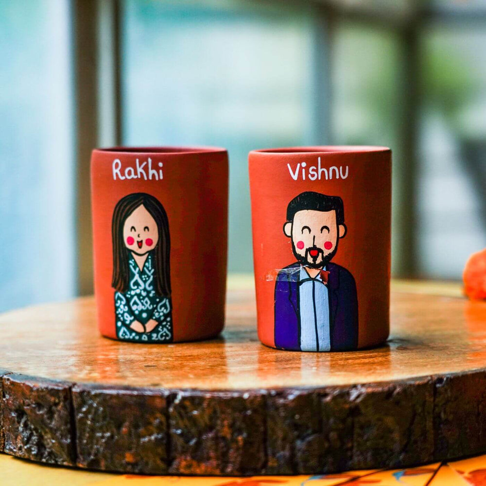 Personalized Terracotta Tumbler Rakhi Set With Caricature - Close-up of Mugs on Wooden Surface