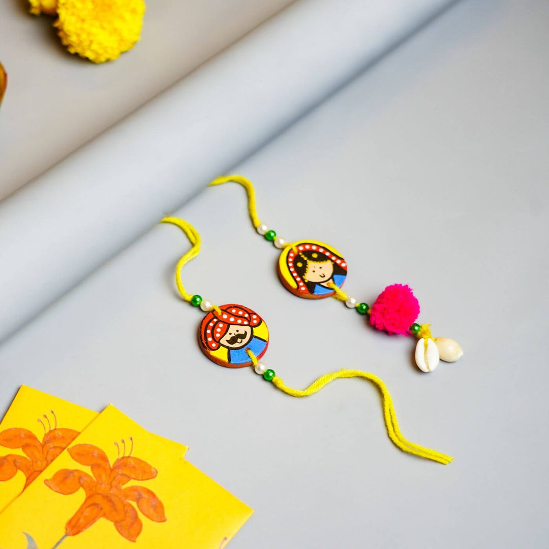 Personalized Terracotta Mug Rakhi Set With Caricature - Flat Lay of Two Character Rakhis
