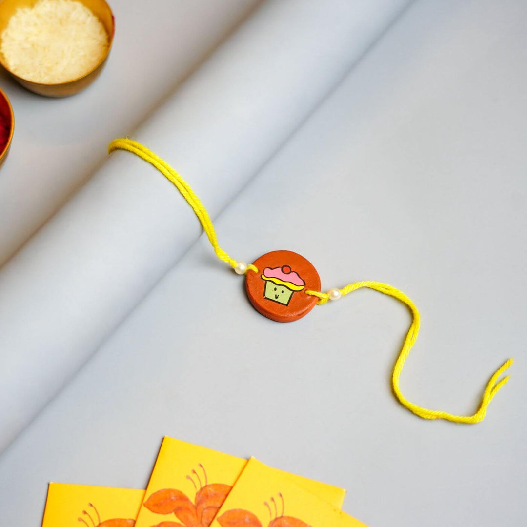 Personalized Food Theme Terracotta Rakhi With Roli Chawal 5 - Flat Lay with Rice and Sweets