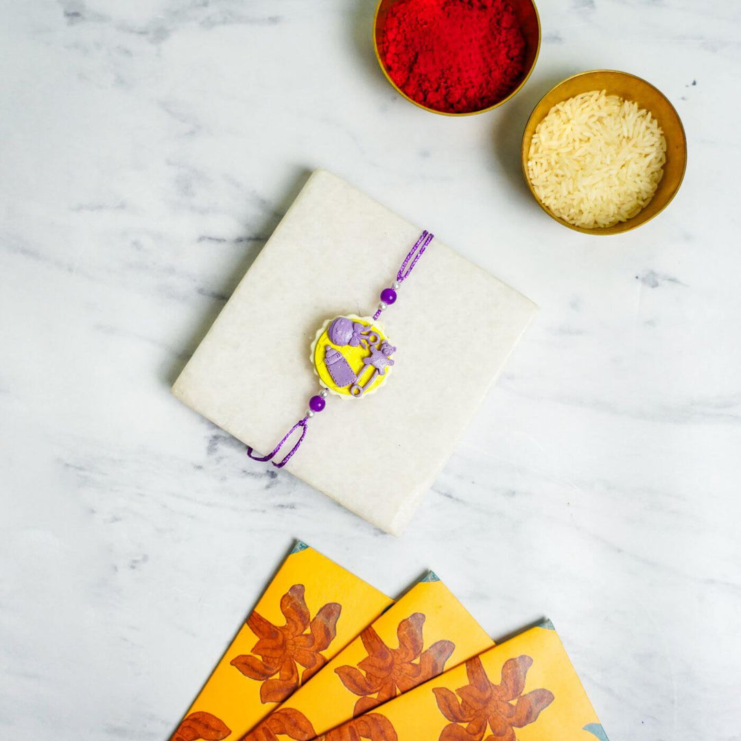 Handmade Porcelain Clay Themed Rakhi 11 - Flat lay with Rakhi and festive items