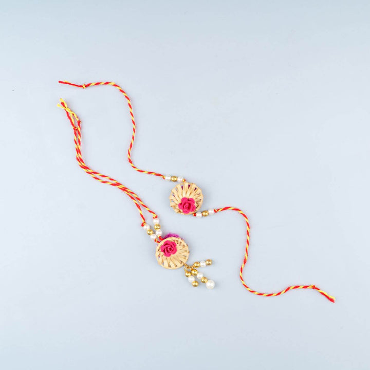 Ecofriendly Bamboo Rakhis For Bhaiya Bhabhi With Roli Chawal 2 - Flat Lay of Twin Rakhi Set with Pink Rose and Tassels