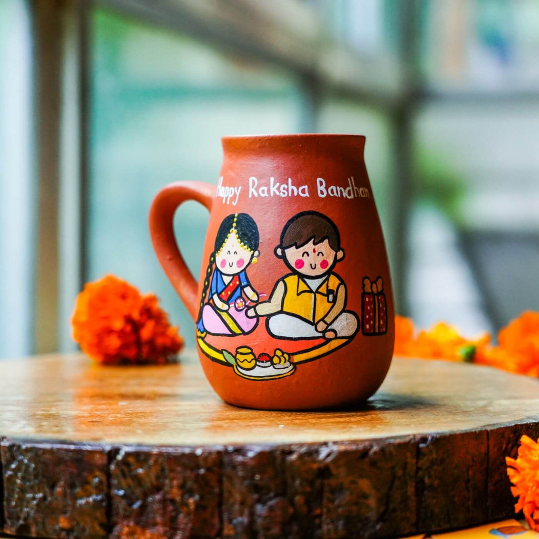 Handpainted Terracotta Rakhi Mug Set With Roli Chawal - Close-up on cup on wooden base