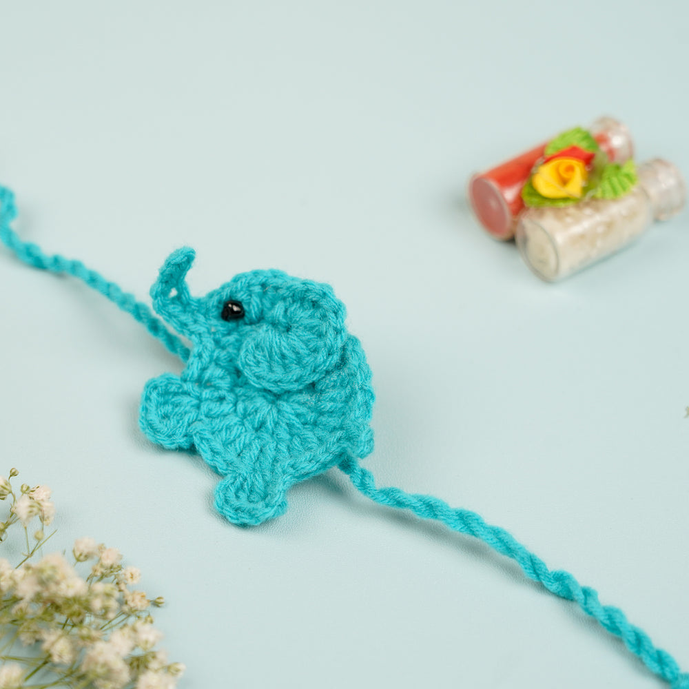 Handmade Crochet Elephant Theme Kids Rakhi With Roli Chawal - Side View with Decorative Bottles